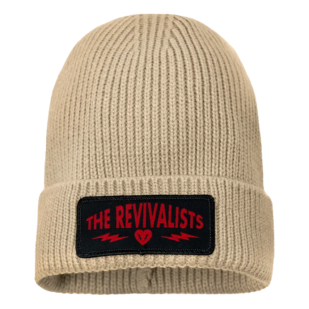 Beige knit beanie with a black patch featuring ’THE REVIVALISTS’ in red text.