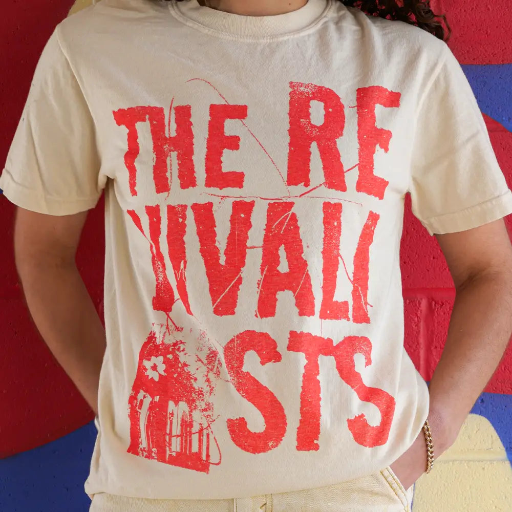 White t-shirt with red text reading ’THE REVIVALISTS’ worn by a person.