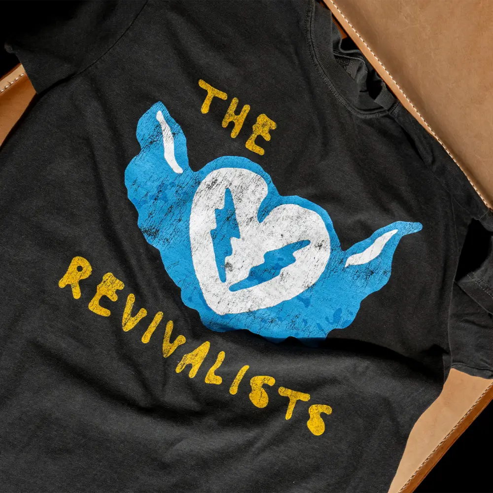Black cotton heart stop tee with distressed blue and white winged heart graphic and yellow the revivalists text