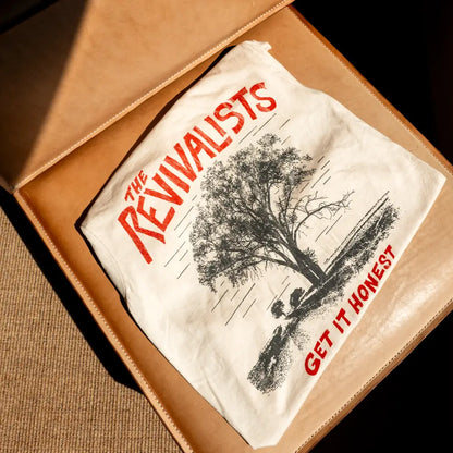 White cotton honest tee featuring a black tree illustration with two figures and bold red text the revivalists get it honest