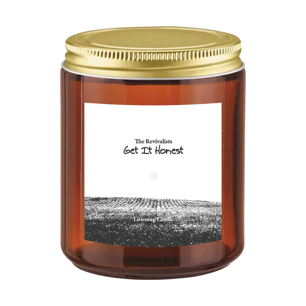 Amber glass sun ray candle jar with gold lid and field illustration labeled the revivalists get it honest candle pre order