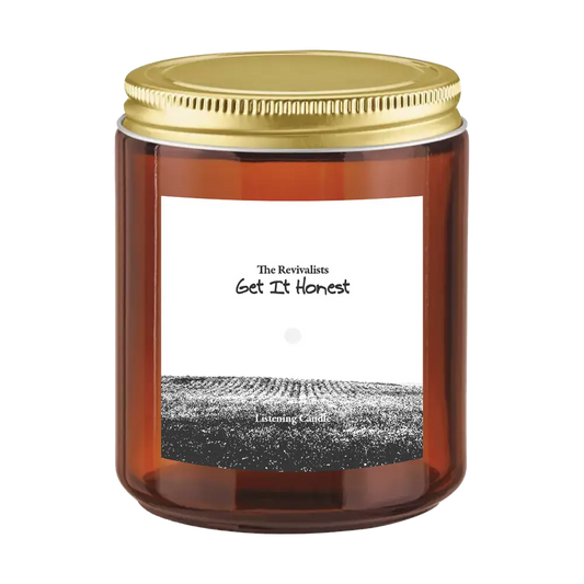 Amber glass sun ray candle jar with gold lid and field illustration labeled the revivalists get it honest candle pre order