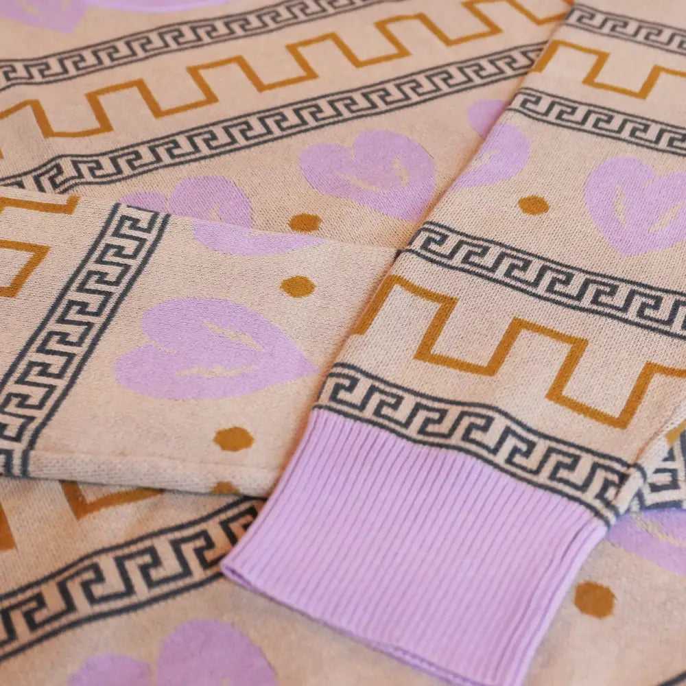 Patterned fabric or textile with Greek key designs and floral motifs in lavender and orange hues.