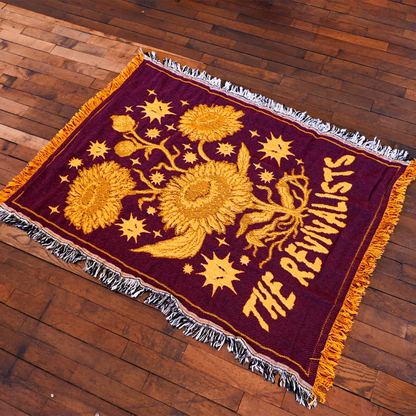 Maroon revivalists woven blanket with gold sunflower and star motifs and bold the revivalists text design