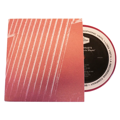 Vinyl record partially removed from its pink and white striped sleeve.